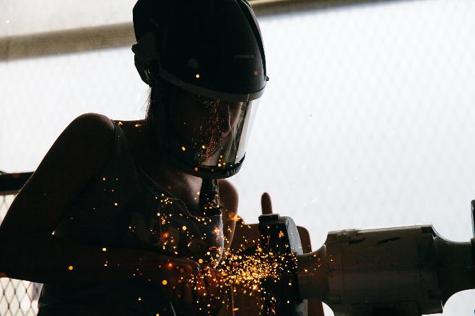 person standing beside gray bench grinder